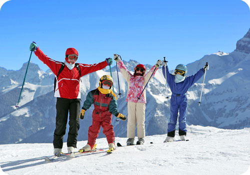 enfants au ski qui posent pour la photo en levant les bras